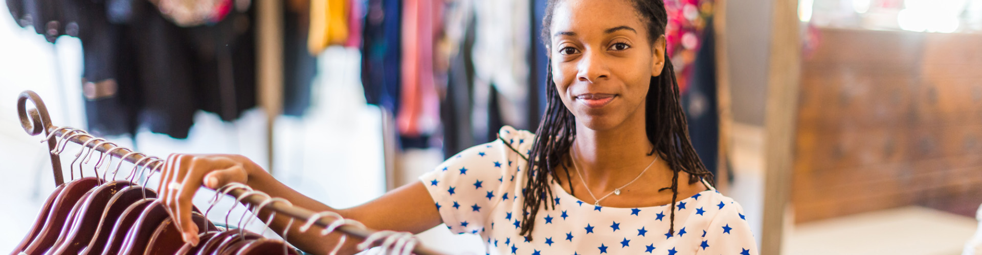 Woman poses next to clothing rack