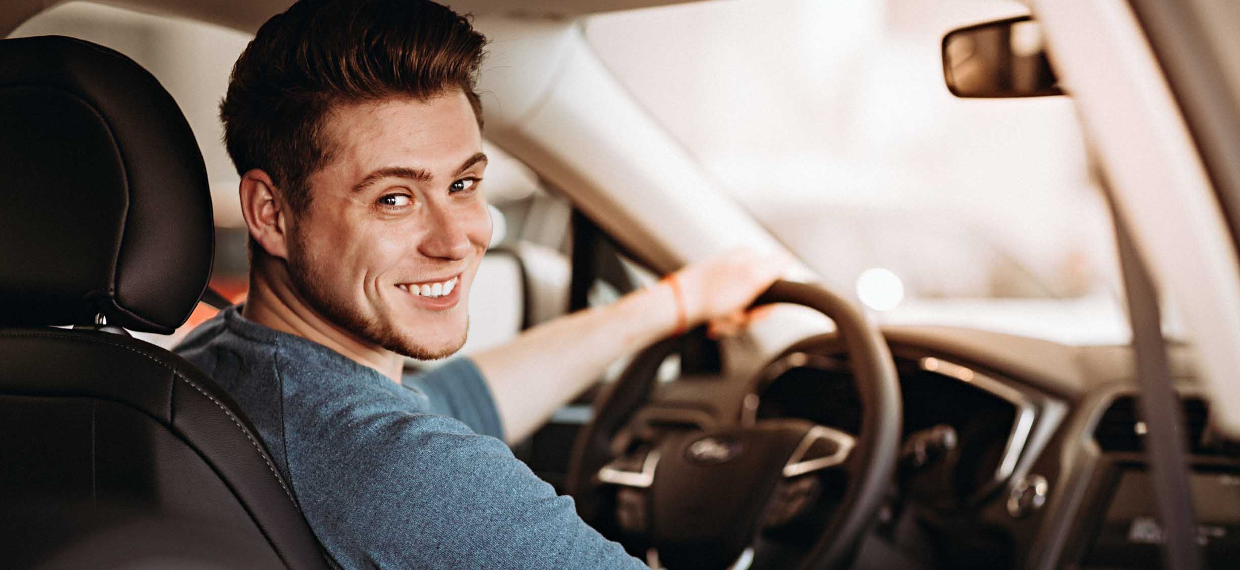 Man smiles over his shoulder while driving car