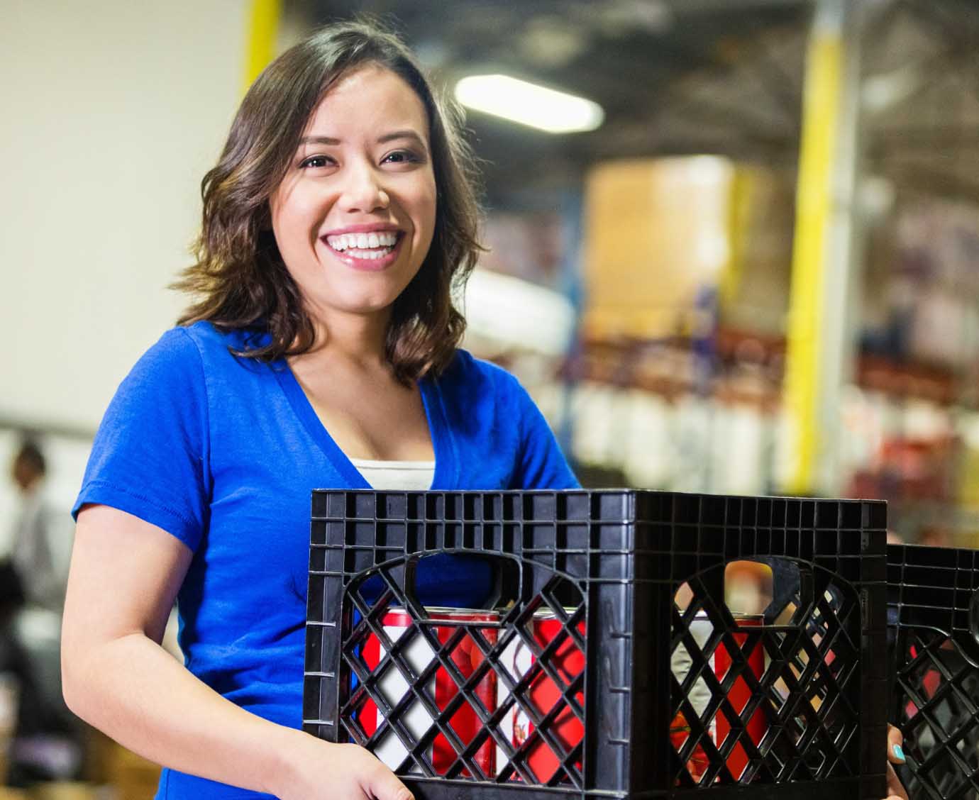 Woman smiles while carrying a crate of products