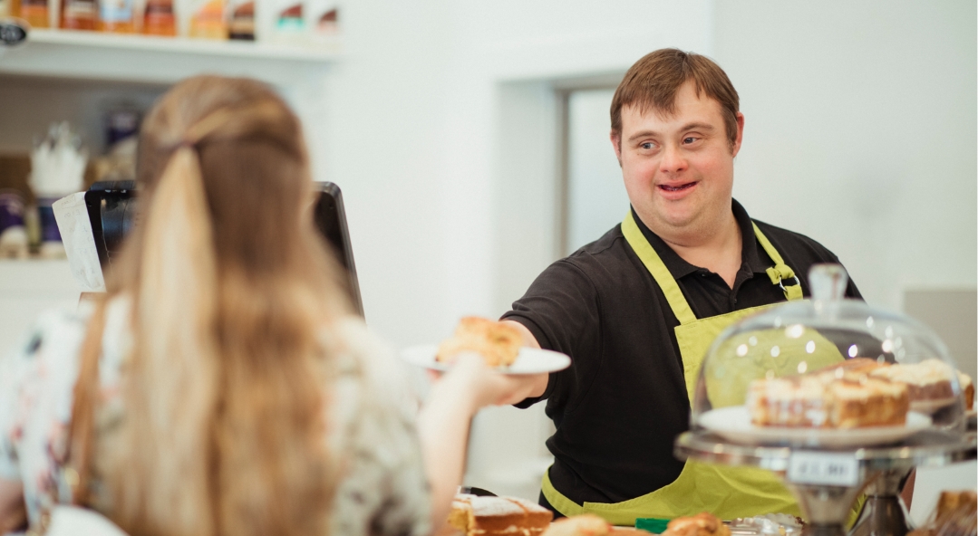 Young male serves pastry to customer