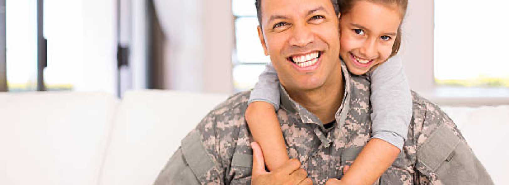 Male service member poses with child on his shoulders.