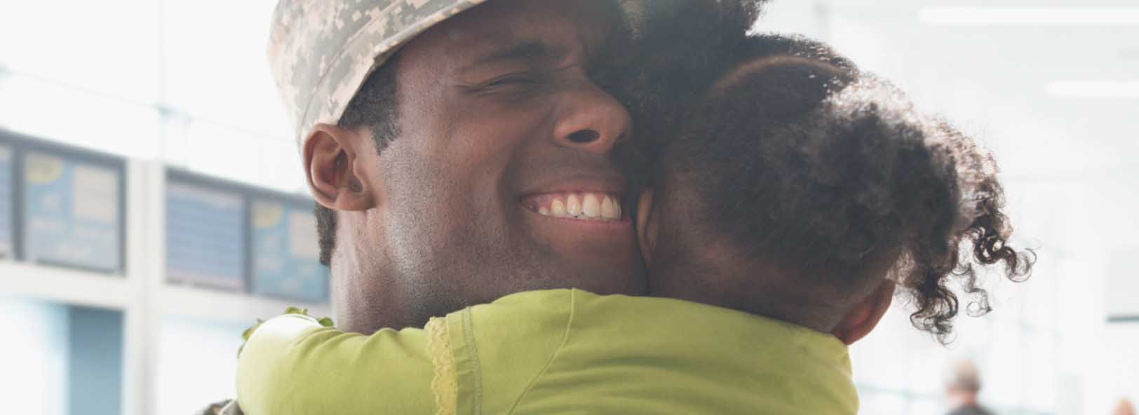 Male service member hugs child