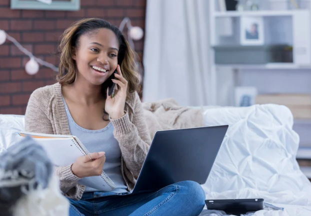 woman smiling on the phone while sitting in her dorm