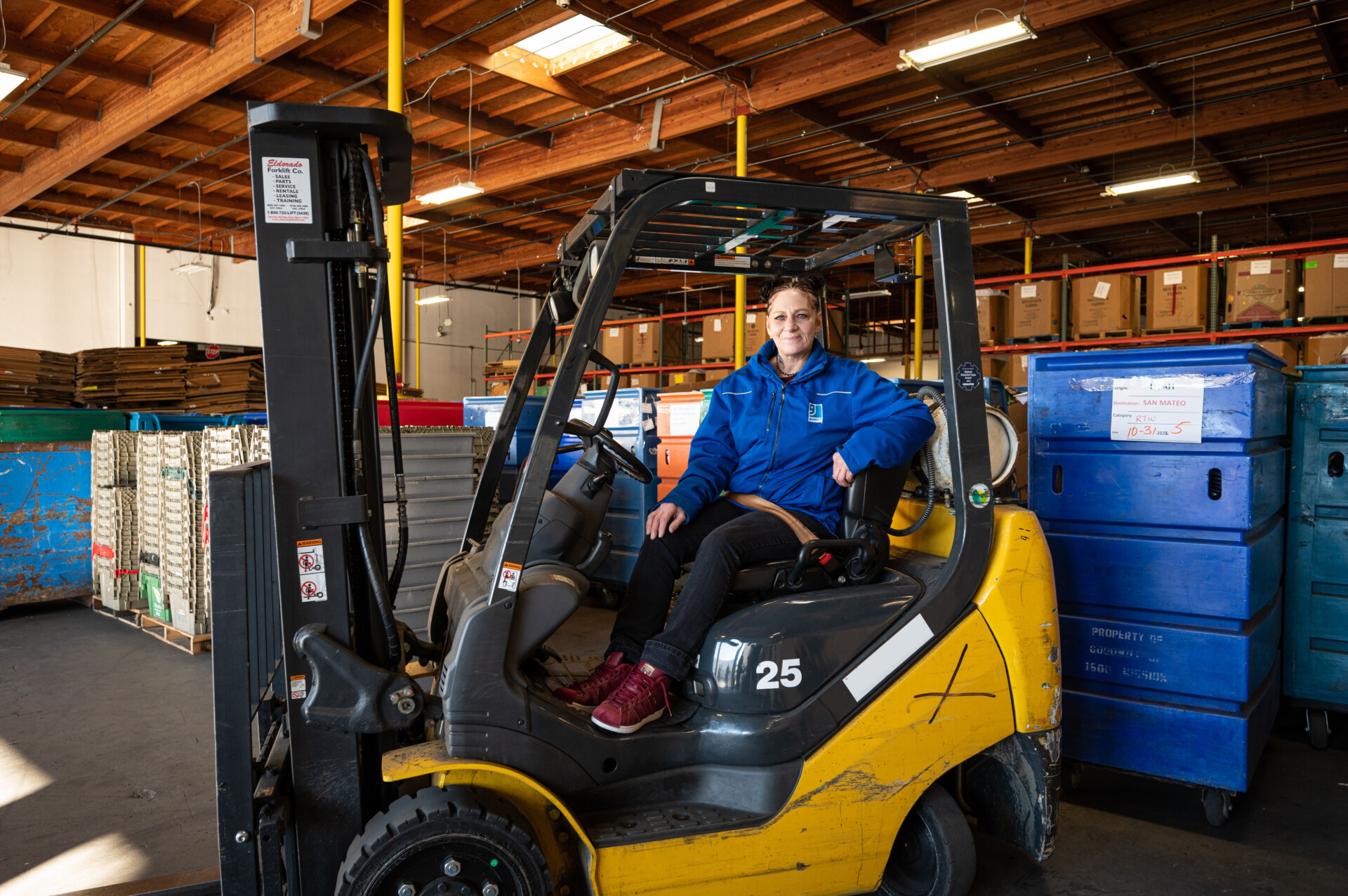 Warehouse worker sitting on forklift indoors
