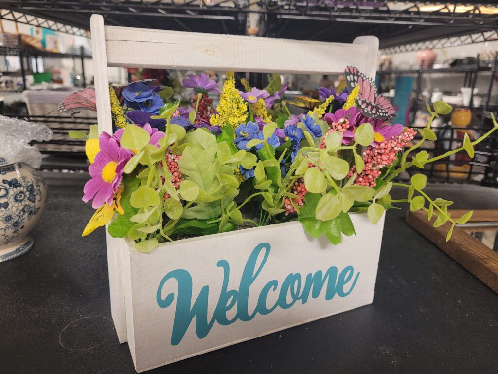 white basket with faux flowers and Welcome written on it