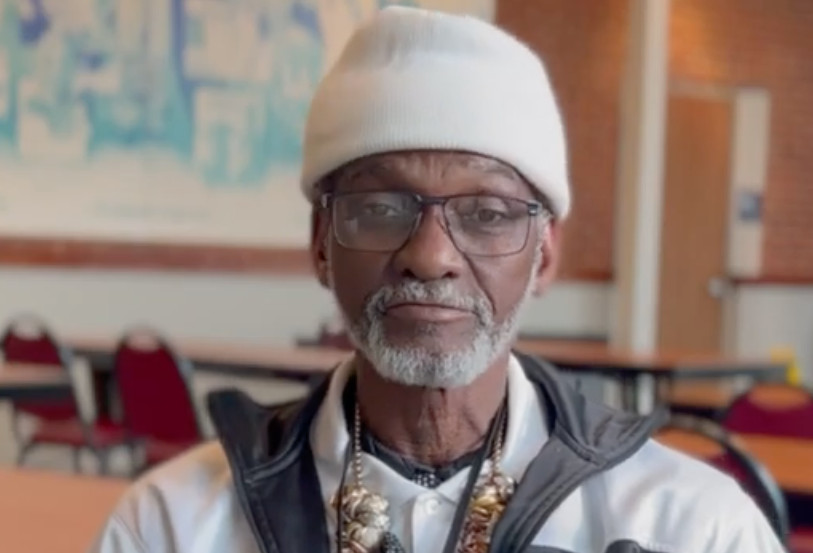 Elderly man wearing beanie and glasses indoors