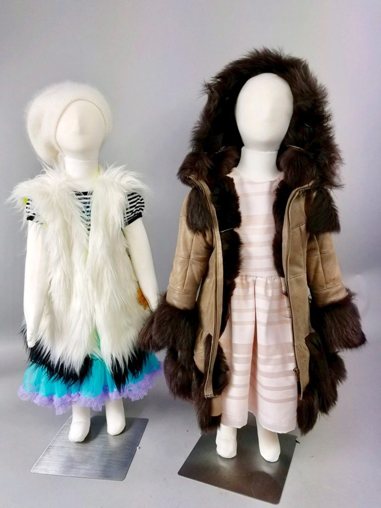 Two small mannequins displaying fur vests and coats