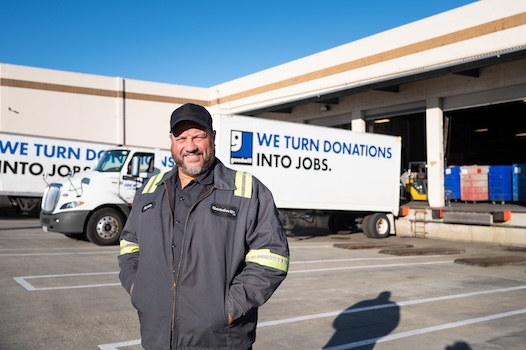 Man standing before Goodwill donation trucks outside warehouse