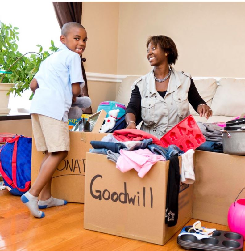 Mother and son sorting clothes in cardboard boxes to donate to Goodwill