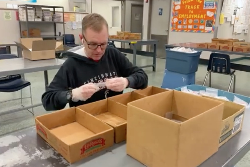 Man assembling items at table with cardboard boxes