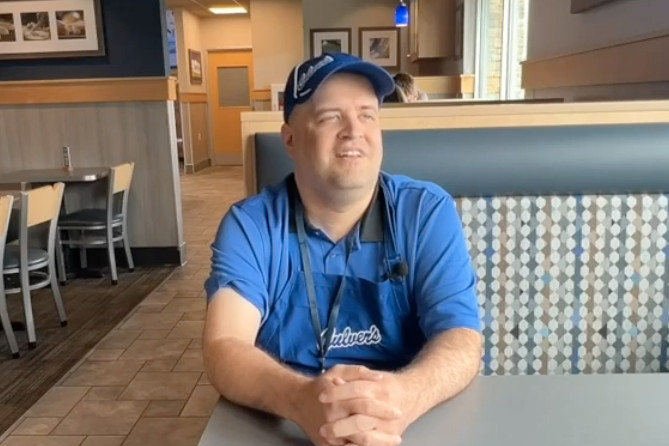 Man in blue uniform sitting in restaurant booth