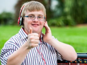 Young male listening to music with headphones and giving a thumbs up