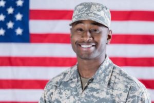 Veteran in Uniform Smiling in front of American Flag 