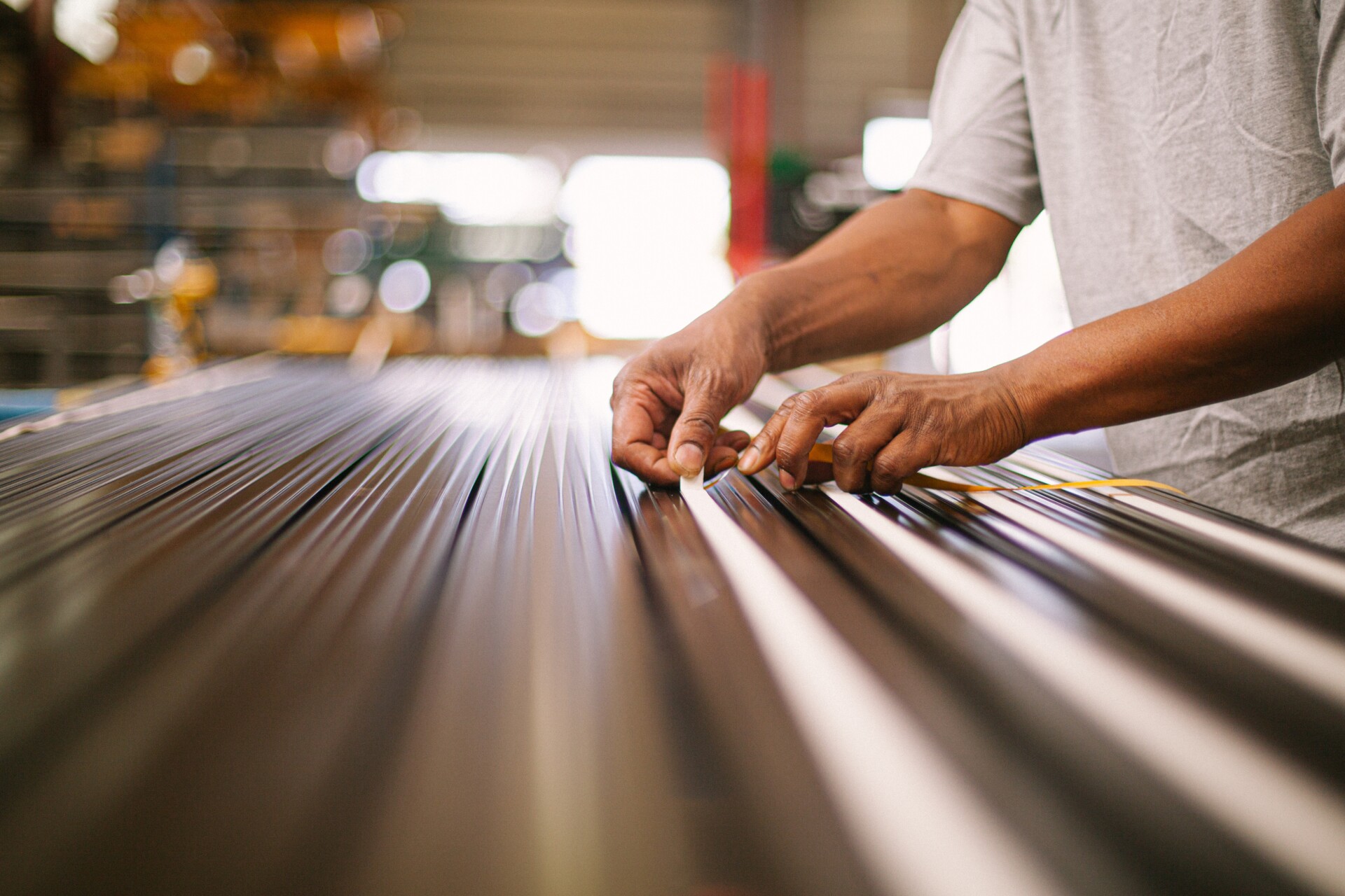 Worker measuring metal sheets in manufacturing workshop