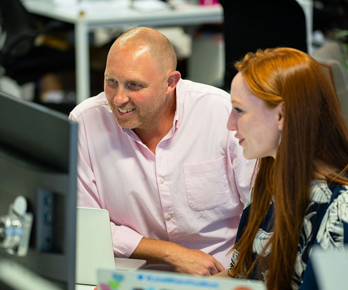 Two coworkers collaborating at computer in office