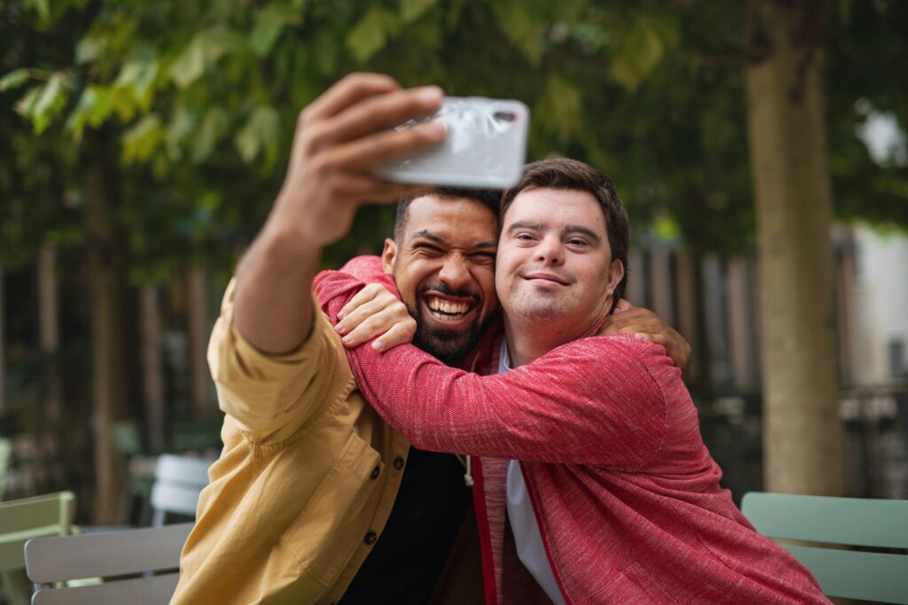 Two men hugging while taking selfie outdoors