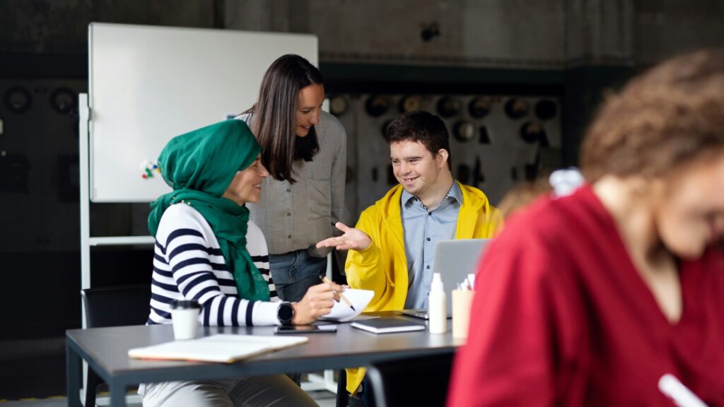 Three coworkers collaborating at table with laptop