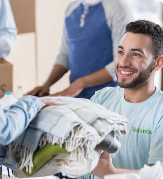 Smiling volunteer handing folded blankets to person
