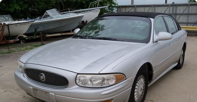 Silver sedan parked near boats outdoors