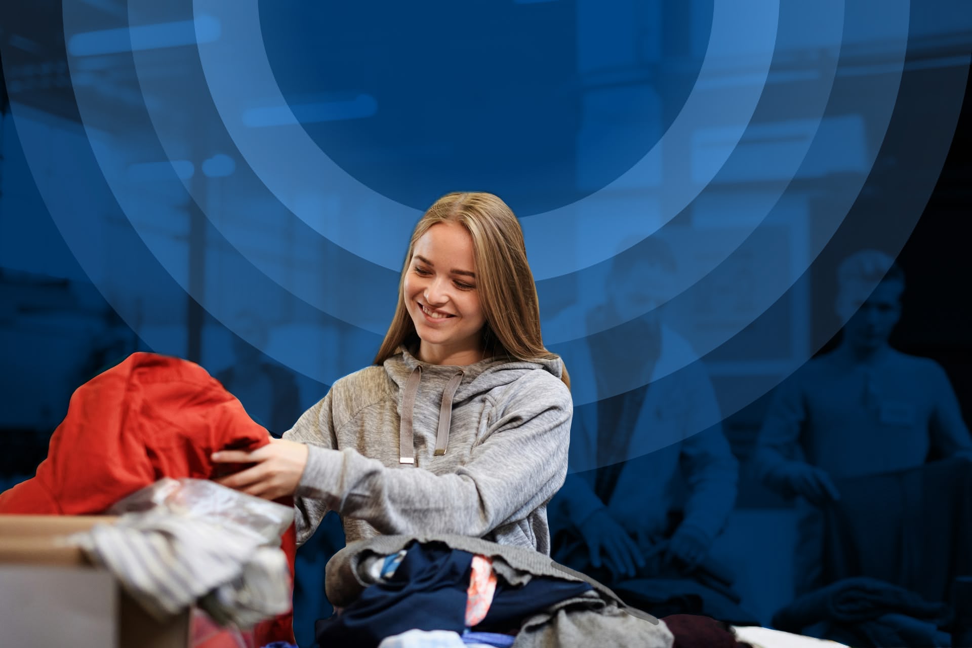 Smiling woman sorting donated clothes from box