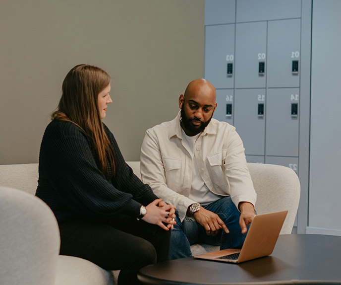 Two coworkers reviewing laptop in office lounge