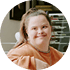 Smiling woman in orange top resting her head on hand